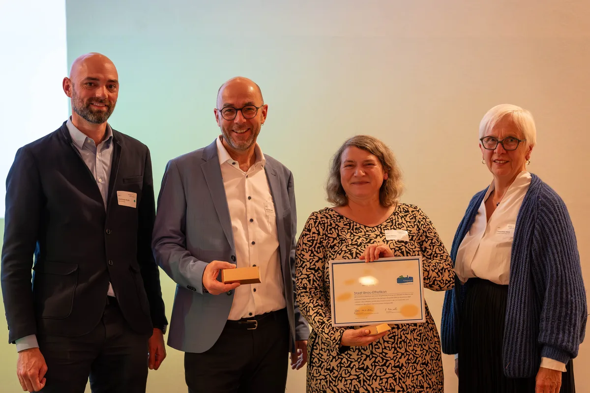 Alex Herzog, Leiter Energie, und Stadtplanerin Ivana Vallarsa nehmen das Energiestadt-Gold-Label in Empfang. Zwei Personen nehmen ein Diplom entgegen.